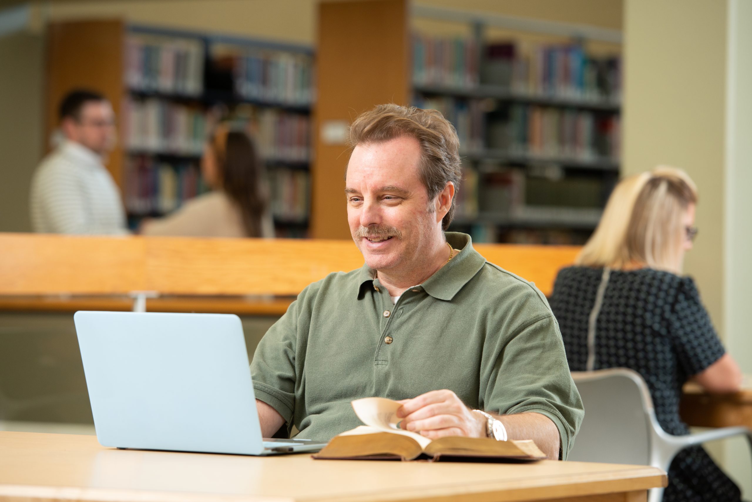 man in library using a laptop